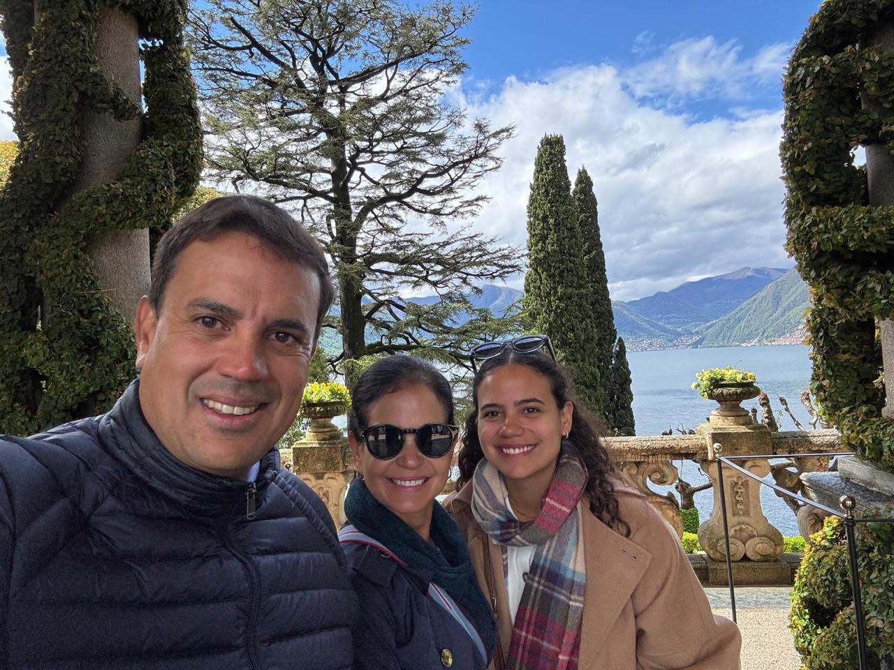 María Isabel y Ho Chi Vega México Una sonriente familia de tres posa al aire libre con el pintoresco lago Como al fondo.