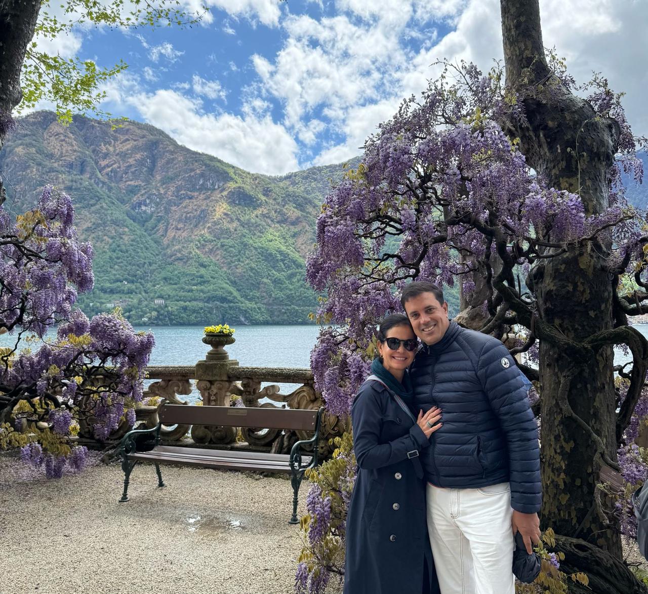 María Isabel y Ho Chi Vega México Pareja sonriendo bajo unas glicinas, con las montañas y un lago como telón de fondo.