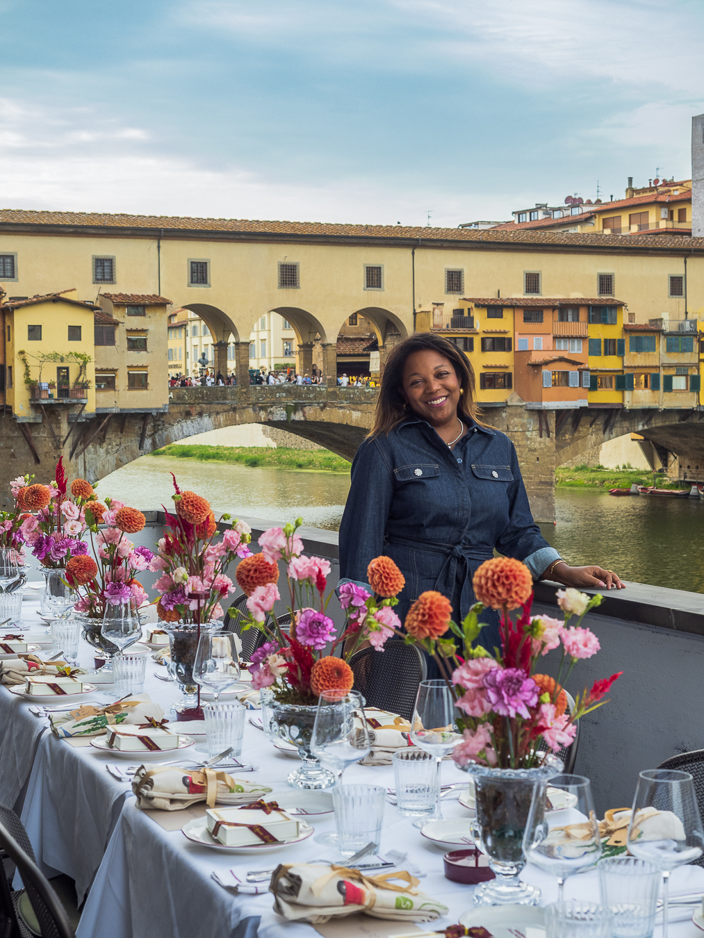 Mesa privada frente al Ponte Vecchio en Florencia Mesa de autor decorada con flores de colores en una terraza frente al Ponte Vecchio, sobre el río Arno en Florencia