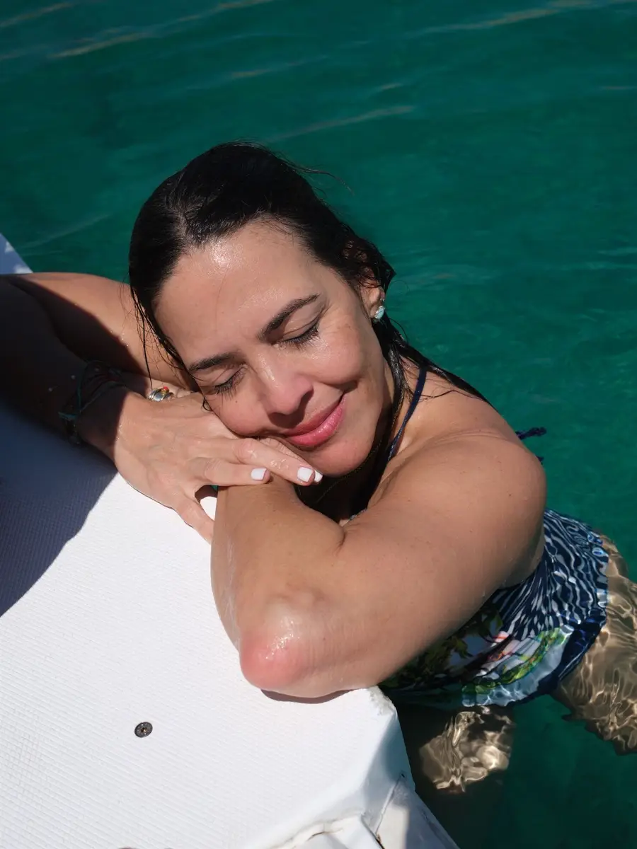 Viajera sonriendo apoyada en la barca mientras se baña en el mar de Capri