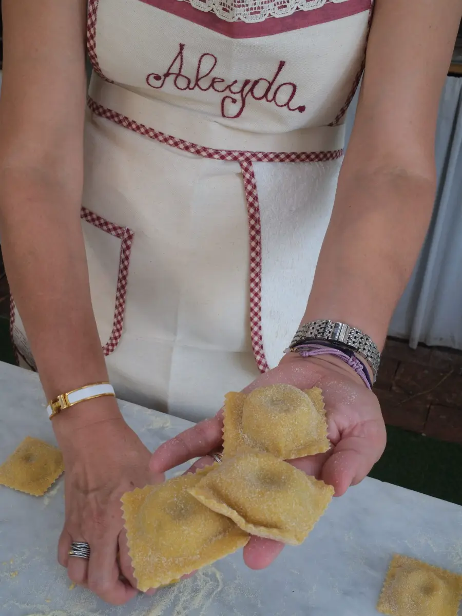 Manos mostrando pasta fresca hecha en una clase de cocina