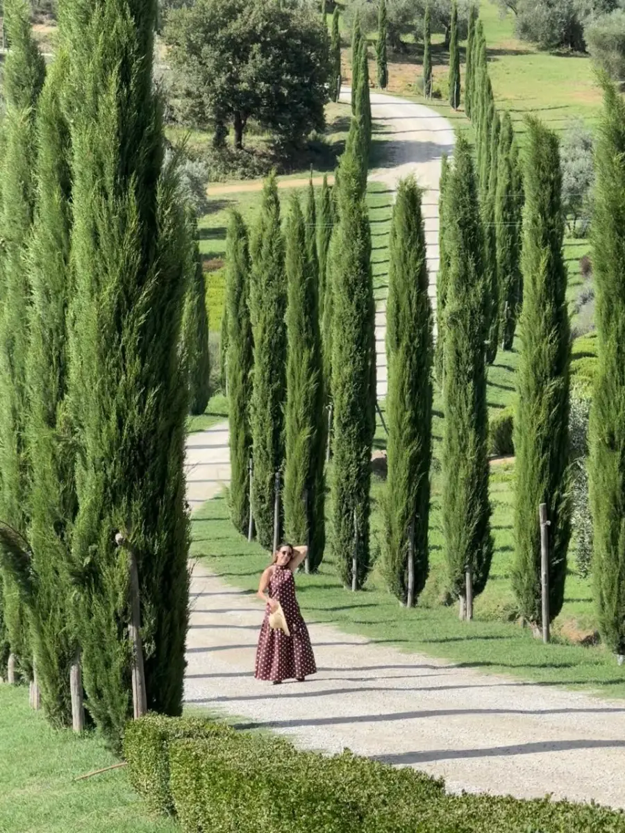 Viajera caminando por un camino de cipreses en la campiña toscana