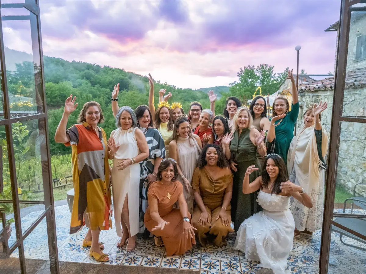 Grupo de viajeras celebrando juntas con los brazos en alto al atardecer