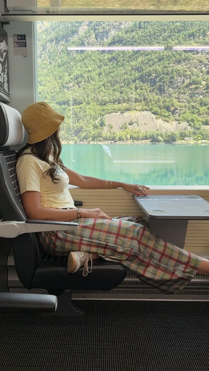 Viajera mirando un lago de montaña desde la ventanilla del tren
